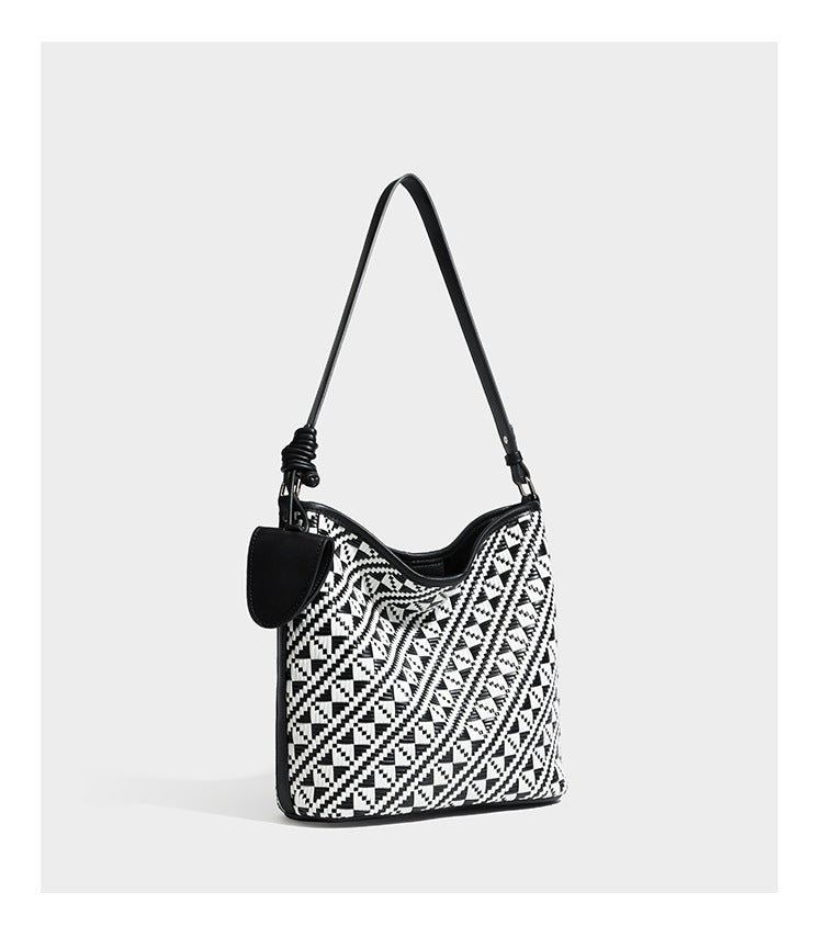 Geflochtene Schultertasche mit geometrischem Ethno-Muster, Besatz in dunkelbrauner Lederoptik, langem verstellbarem Träger und kleinem hängendem Reißverschluss
