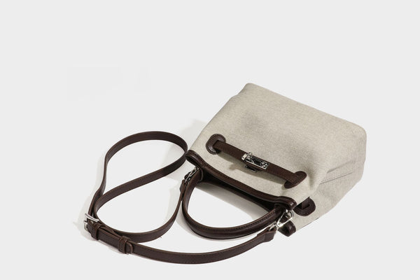 Small structured beige canvas top-handle bag with dark brown leather-look trim, silver turn-lock hardware, and detachable