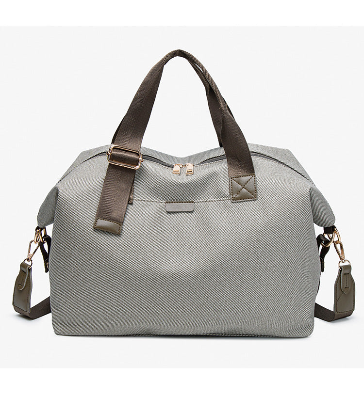 Structured woven duffel bag with dual tan webbing handles, detachable shoulder strap, top zip closure, and gold-tone