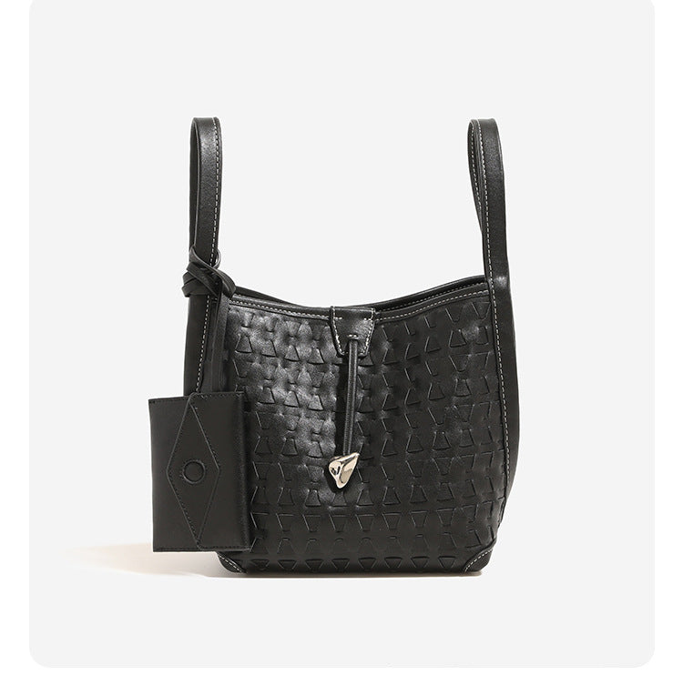 Cremefarbene Bucket Bag mit geometrischem Dreiecksrelief, schmalem Schulterriemen, goldfarbenem Dreiecksanhänger und abnehmbarer Mini-Tasche mit Druckknopfverschluss