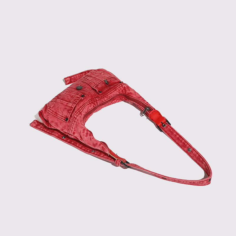 Compact washed red distressed-textile shoulder bag with front flap pockets, dark metal hardware, and long adjustable strap