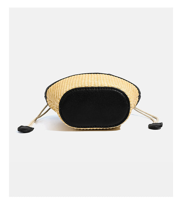 Kleine geflochtene Bucket Bag aus Stroh mit schwarzem Besatz in Lederoptik, zwei oberen Tragegriffen, cremefarbenem Futter mit Kordelzug und seitlichen Kordelverschlüssen