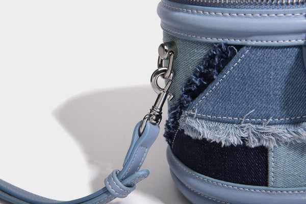 Mini cylindrical barrel bucket bag in denim patchwork with frayed edges, smooth leather-look trim, zip-around top closure