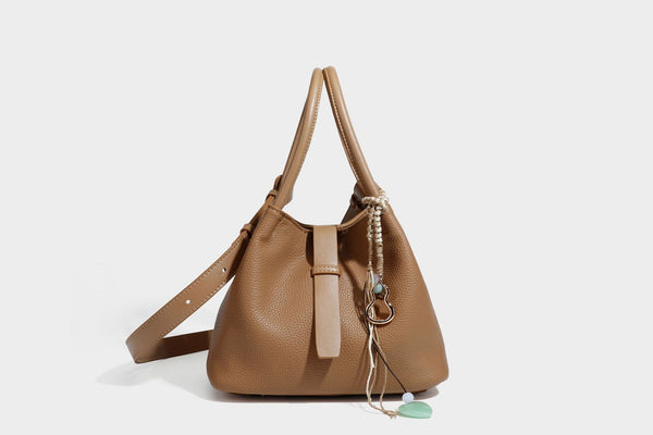 Pebbled leather-look bucket tote bag with rolled double handles, drawstring closure, braided cord charm, and detachable