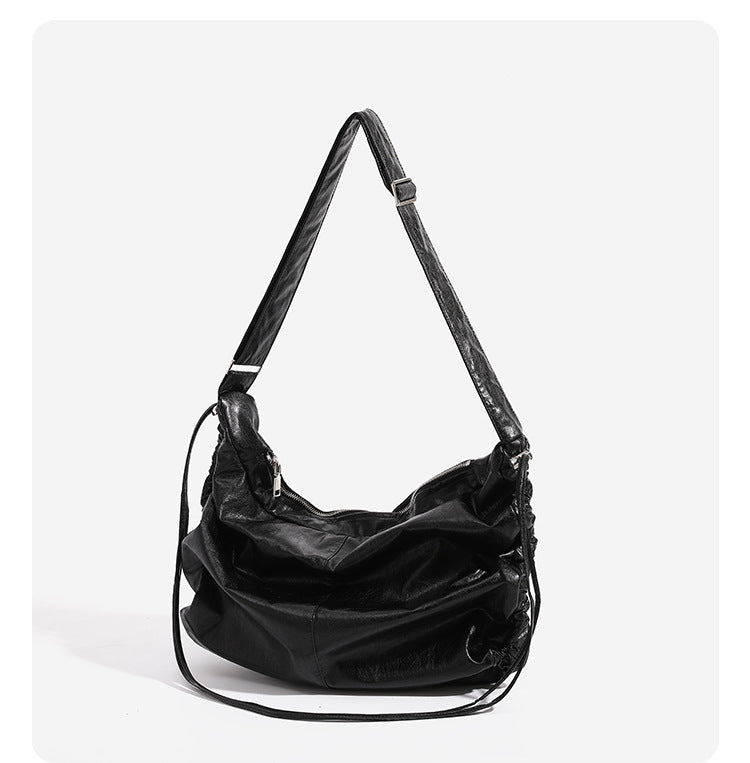Oversized slouchy hobo shoulder bag with glossy crinkled leather-look finish, drawstring gathered sides, and silver-tone