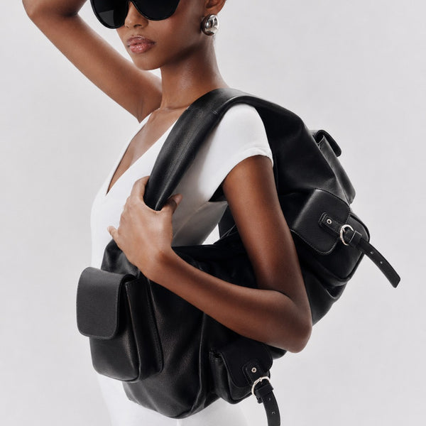 Oversize-Schultertasche in Schwarz mit weicher, lederähnlicher Oberfläche, vier Klappentaschen mit Schnallen und breitem, gepolstertem Henkel an der Oberseite, Detailansicht 2