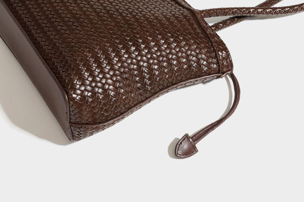 Structured woven leather-look tote bag in dark brown with long shoulder straps, side drawstring ties, and gold filigree