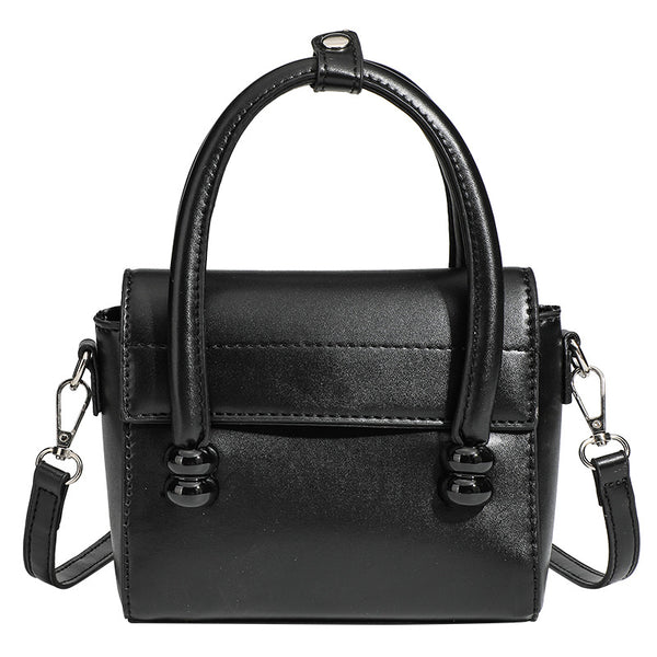 Kleine strukturierte schwarze Henkeltasche im Lederlook mit zwei abgerundeten Henkeln, abnehmbarem Umhängeriemen und silberfarbenem