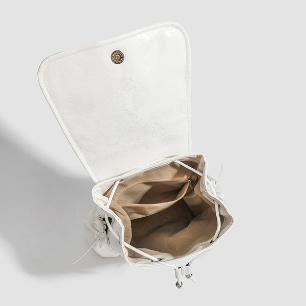 Compact white pearlescent flap backpack with silver-tone bow hardware and drawstring closure, detail view 4
