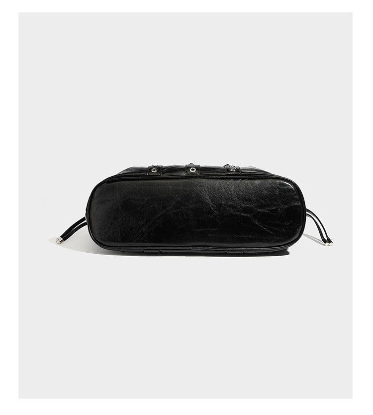 Large black glossy leather-look tote bag with silver buckle straps, eyelet grommet panels, drawstring side gathers, and