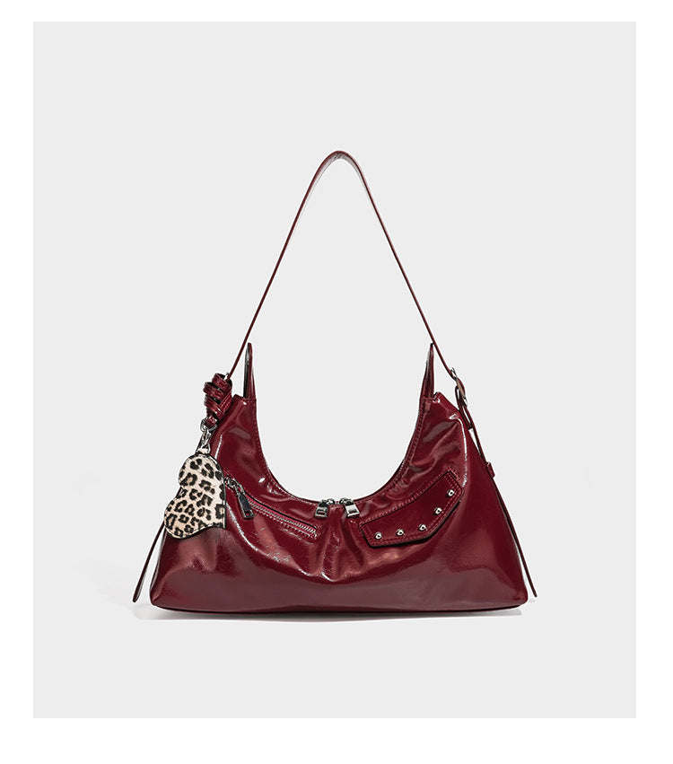 Glossy dark brown hobo shoulder bag with slim strap, front zip pocket, stud detail, and detachable leopard-print heart charm
