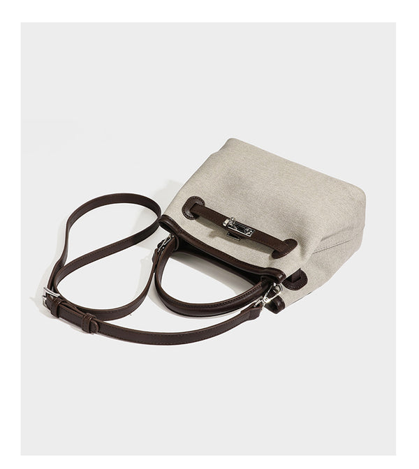 Small structured beige canvas top-handle bag with dark brown leather-look trim, silver turn-lock hardware, and detachable