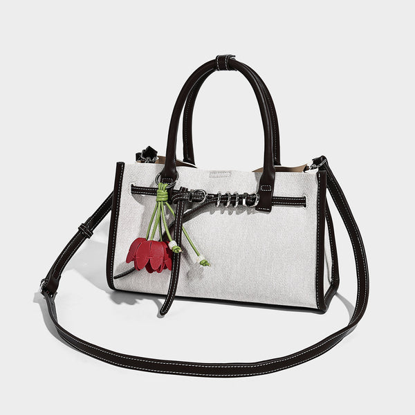 Structured rectangular tote satchel in denim-look fabric with dark trim, knotted front strap hardware, and detachable, detail