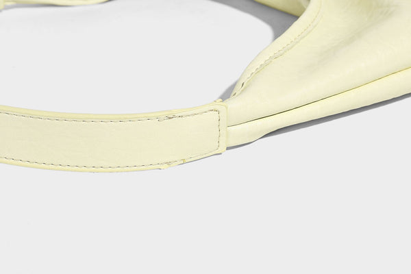 Slouchy hobo shoulder bag in pale yellow glossy pebbled leather-look finish with single shoulder strap and detachable front