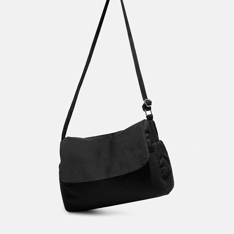 Große Messenger-Bag aus mattem schwarzem Canvas mit Frontklappe, Reißverschluss oben, elastischen Seitentaschen und verstellbarem silberfarbenem