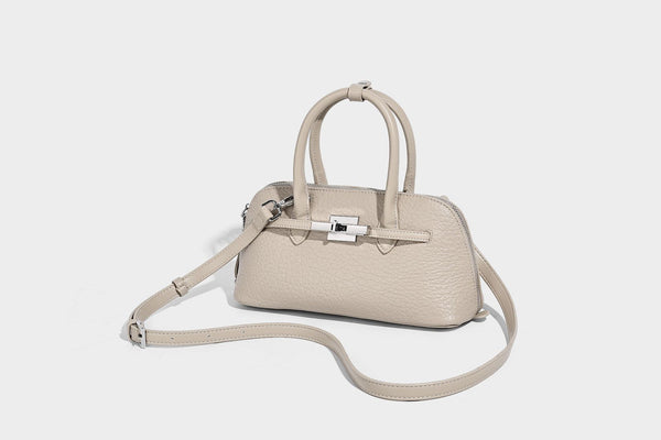 Small structured shell-silhouette top-handle bag with pebbled leather-look finish, silver-tone turn-lock hardware, and