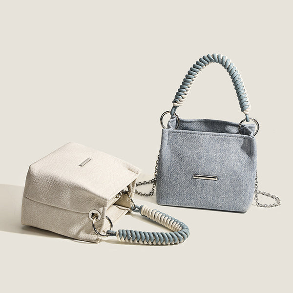 Small structured trapezoid mini bag with coiled rope top handle and silver-tone chain strap in textured fabric, detail view 2