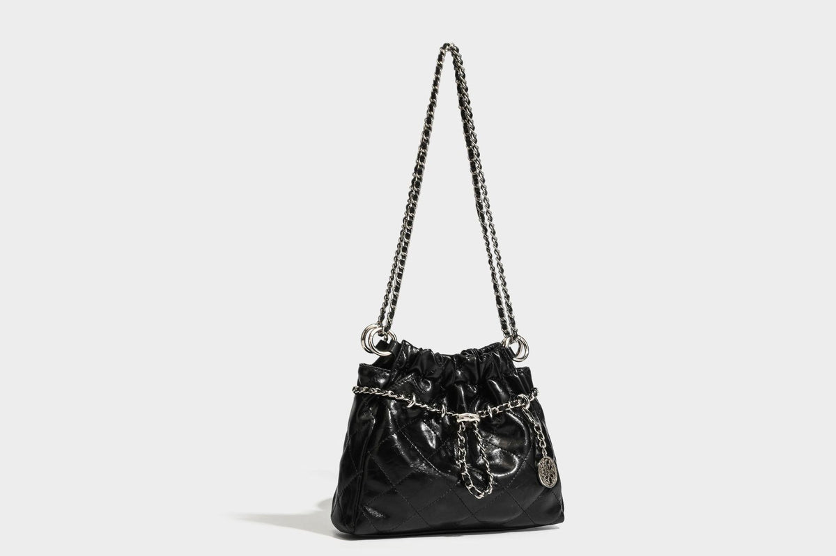 Glossy diamond-quilted drawstring bucket bag with silver chain shoulder strap and medallion charm, detail view 27