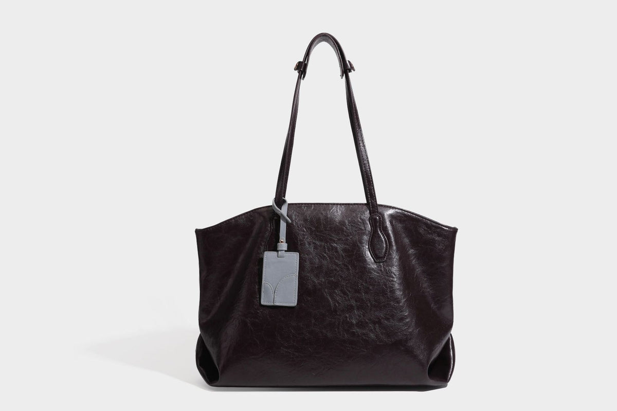 Übergroße, lässig fallende Tote-Bag aus glänzendem, geknittertem Lederimitat in dunklem Burgunderrot mit zwei langen Schulterriemen und kontrastierendem