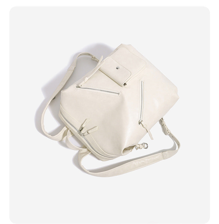 Structured smooth leather-look backpack handbag with dual top zip closure, diagonal front zip pocket, snap-flap mini pocket