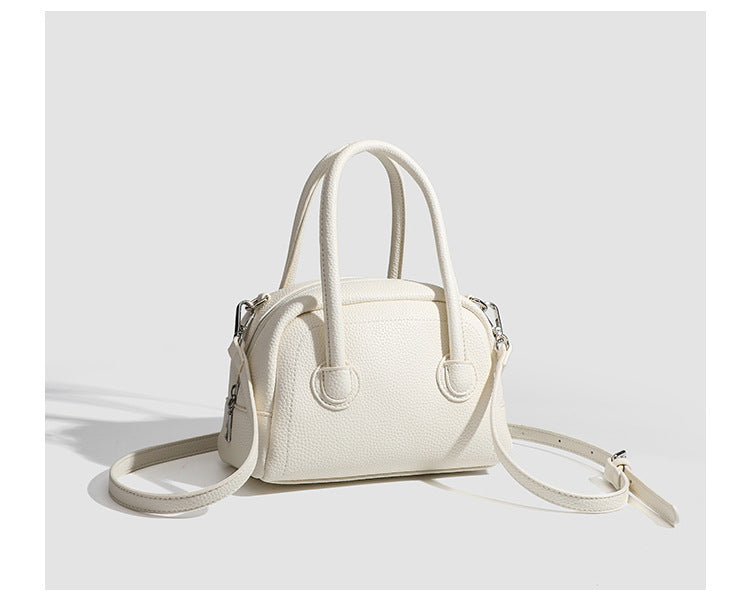 Mini-Boston-Tasche mit genarbtem Finish, zwei Henkeln, abnehmbarem und verstellbarem Crossbody-Riemen sowie silberfarbenen Beschlägen, Detailansicht
