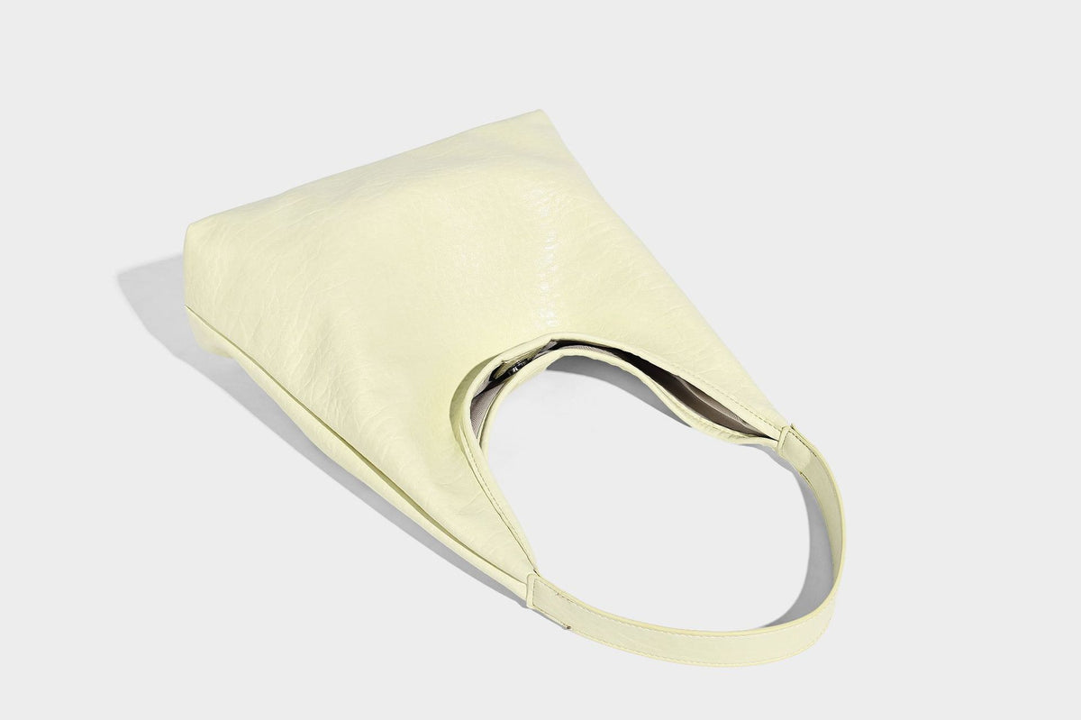 Slouchy hobo shoulder bag in pale yellow glossy pebbled leather-look finish with single shoulder strap and detachable front