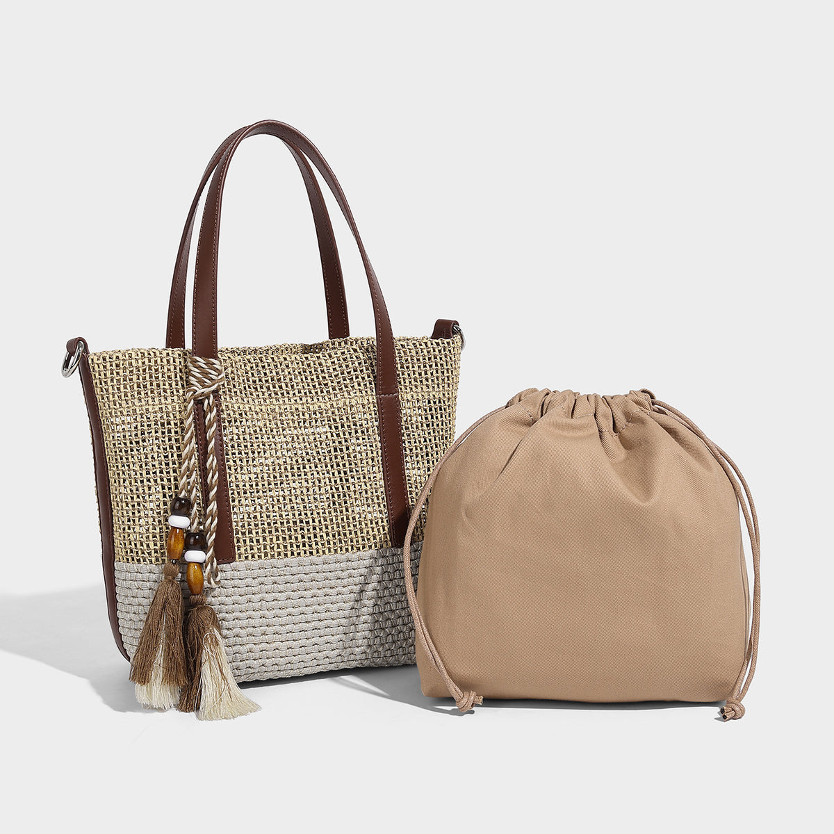 Two-tone open-weave tote bag in beige and cream with brown leather-look handles, tassel bead charm, and detachable