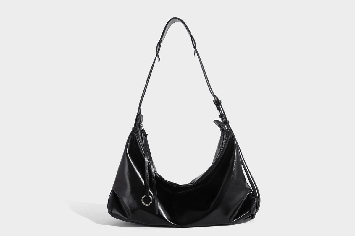 Glossy black slouchy hobo shoulder bag with zip closure, silver-tone ring hardware, and adjustable crossbody strap, detail