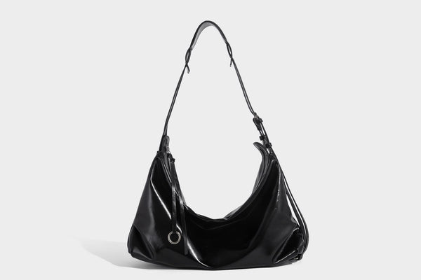 Glossy black slouchy hobo shoulder bag with zip closure, silver-tone ring hardware, and adjustable crossbody strap, detail