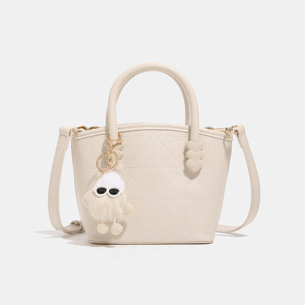 Quilted leather-look mini bucket tote bag with heart-shaped side accents, gold-tone hardware, fuzzy character charm, and