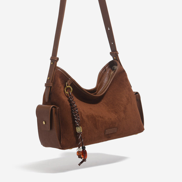 Caramel brown slouchy hobo shoulder bag with matte suede-like finish, braided tassel charm, brass-tone hardware, and, detail