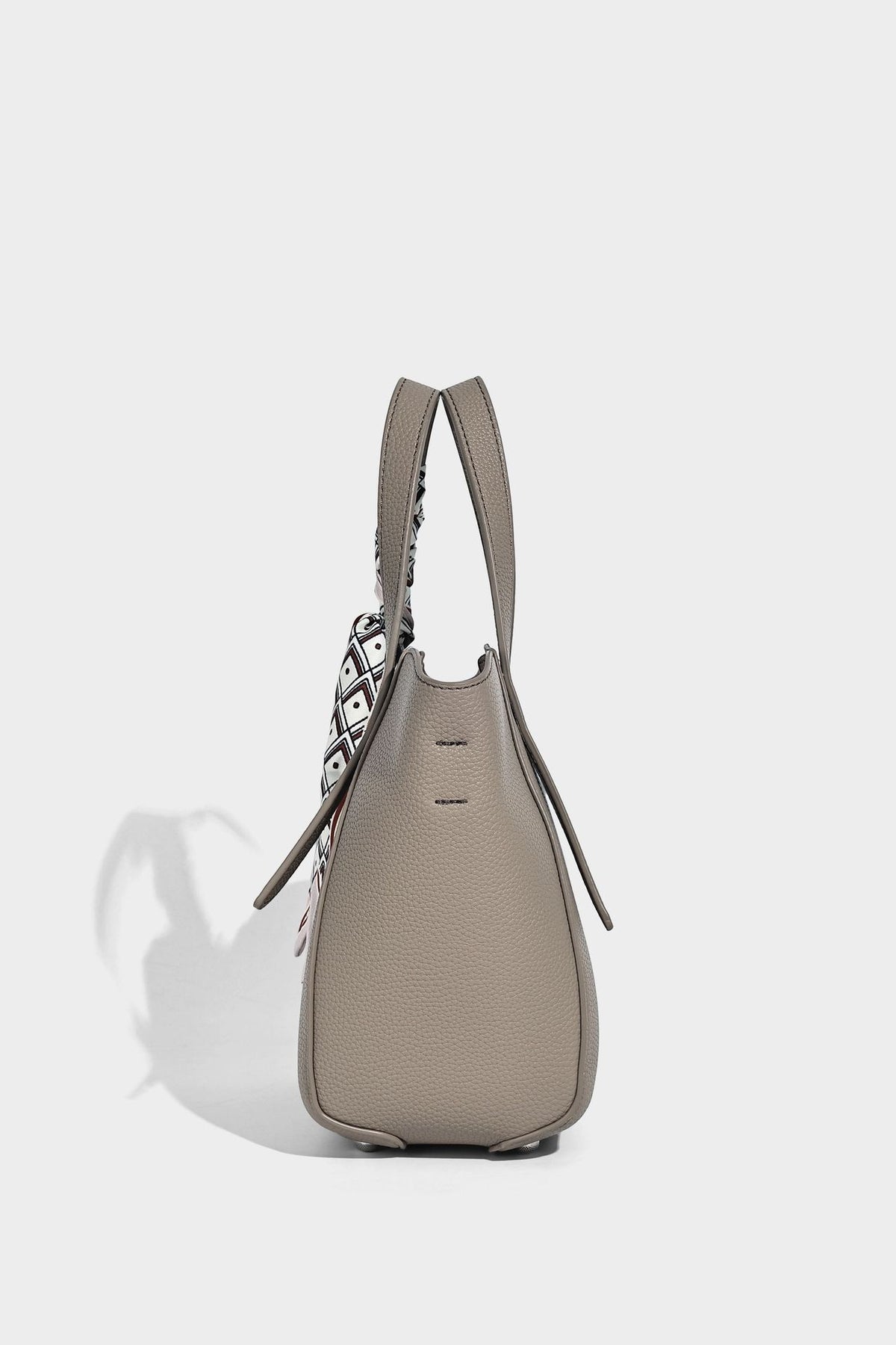 Structured pebbled leather-look tote bag with detachable scarf tie, dual top handles, and adjustable crossbody strap, detail