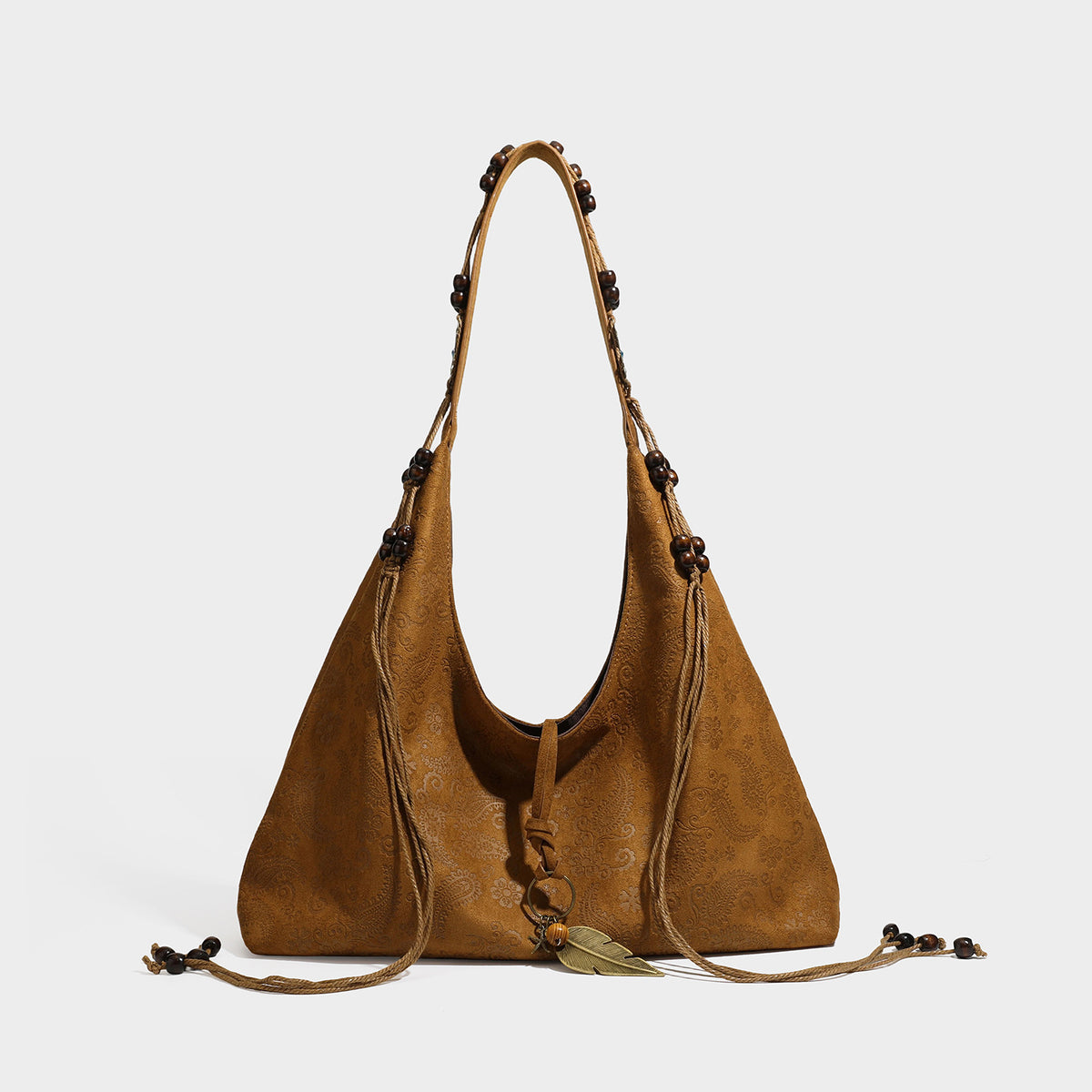 Slouchy boho hobo shoulder bag in embossed brown suede-look finish with beaded strap, cord tassels, and brass-tone leaf
