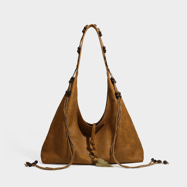 Slouchy boho hobo shoulder bag in embossed brown suede-look finish with beaded strap, cord tassels, and brass-tone leaf