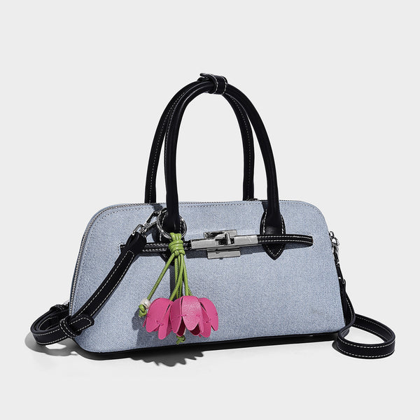 Compact structured satchel in light blue denim-look fabric with black leather-look trim, silver turn-lock closure, rolled