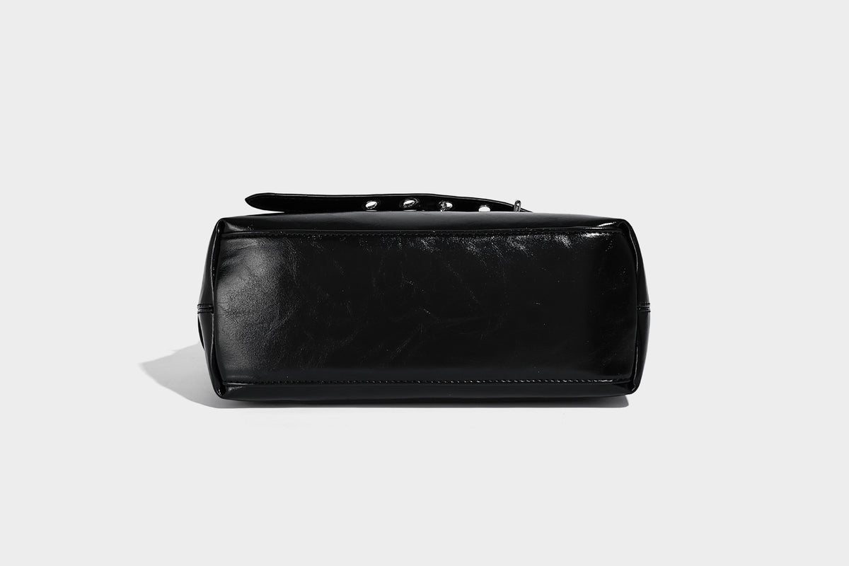 Glossy black slouchy hobo shoulder bag with silver-tone hardware, belt-style grommet strap at base, and long adjustable