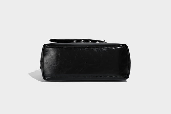 Glossy black slouchy hobo shoulder bag with silver-tone hardware, belt-style grommet strap at base, and long adjustable