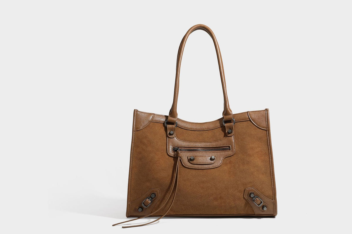 Large structured tote bag with matte suede-like body, smooth leather-look trim, front zip pocket, stud hardware, and