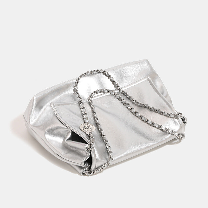 Soft trapezoidal chain-strap shoulder bag with foldover flap and circular logo medallion, detail view 3