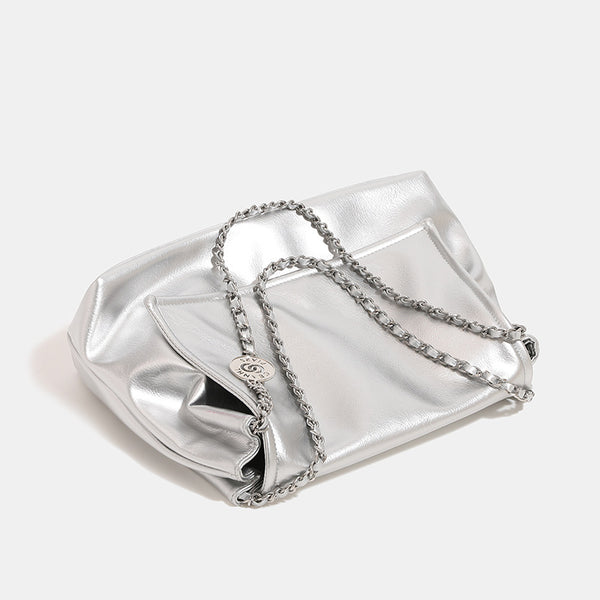 Soft trapezoidal chain-strap shoulder bag with foldover flap and circular logo medallion, detail view 3