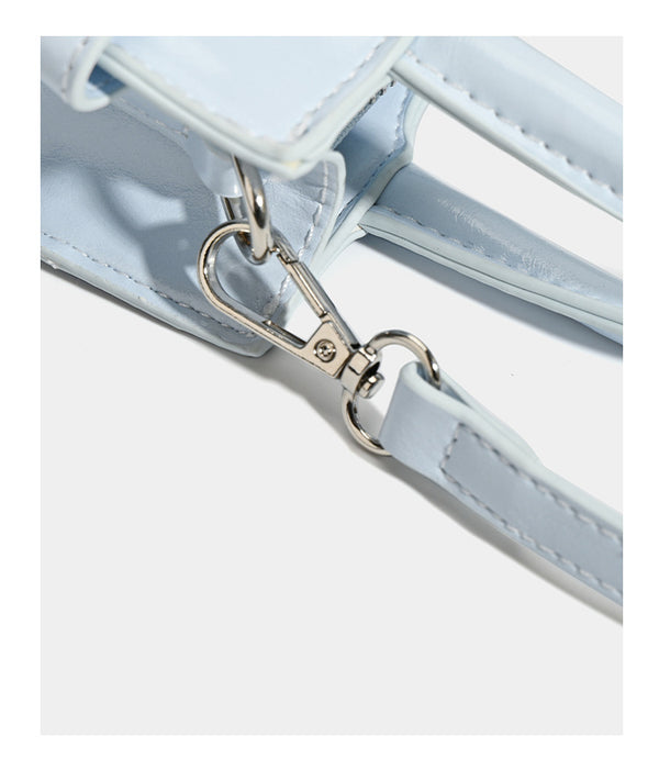 Small structured trapezoid mini top-handle bag with front belt-knot buckle detail and glossy leather-look finish, detail view