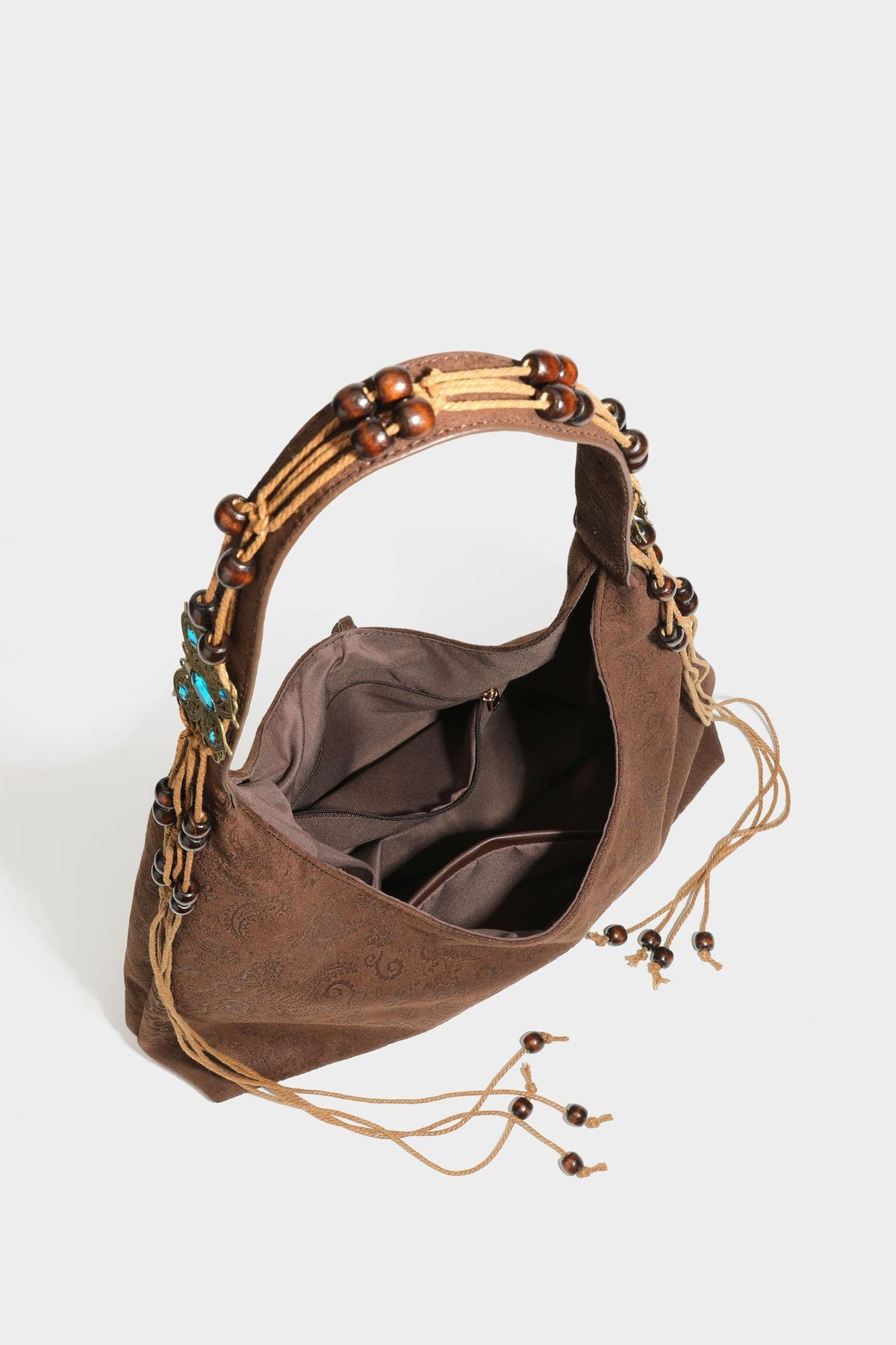 Slouchy boho hobo shoulder bag in embossed brown suede-look finish with beaded strap, cord tassels, and brass-tone leaf