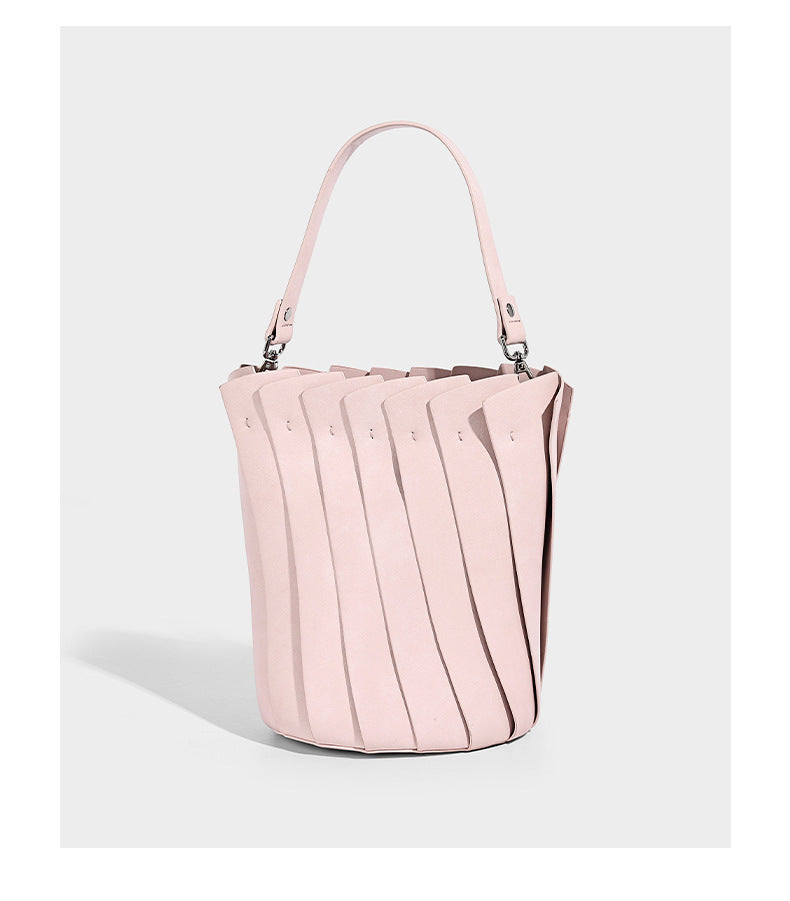Structured pleated-panel bucket bag with curved top handle and detachable adjustable shoulder strap in smooth matte, detail