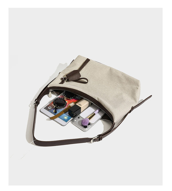 Cream canvas hobo shoulder bag with dark brown leather-look trim, zip-top closure, adjustable strap, and silver-tone