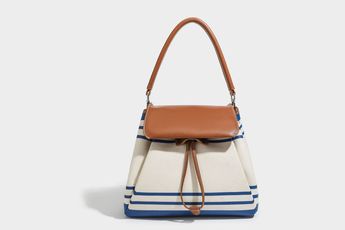 Cream canvas bucket bag with blue horizontal stripes, tan leather-look flap and trim, drawstring closure, silver-tone, detail