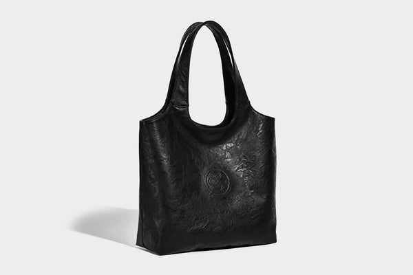 Large open-top tote bag with crinkled leather-look finish, long double shoulder straps, and embossed circular detail on