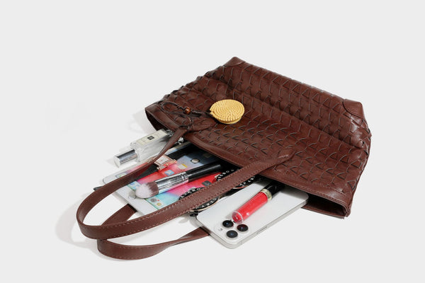 Large leather-look tote bag with geometric woven emboss, double shoulder straps, and round woven cord charm in brown, detail