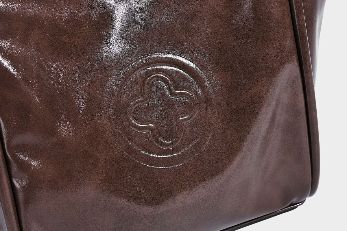 Glossy leather-look structured tote bag with rounded top handles, detachable shoulder strap, embossed front emblem, and side