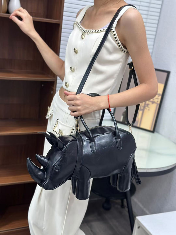 Rhinoceros-shaped 3D structured handbag with sculpted horns, four legs, tassel tail, twin top handles, and detachable, detail