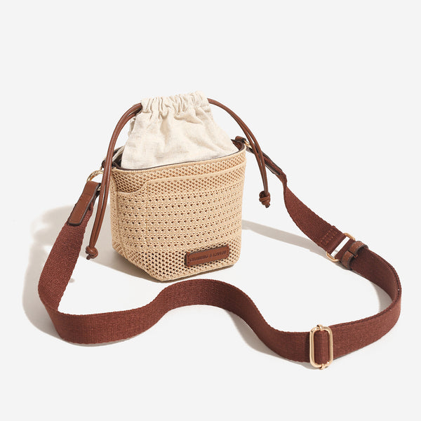 Compact openwork woven bucket bag with gathered cream drawstring liner, leather-look brown trim and cords, and gold-tone